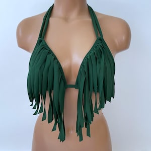 May include: A green halter-top bikini with fringe detailing. The top features a triangular design with long, vertical fringe hanging from the bust. The bikini is displayed on a mannequin against a white background.