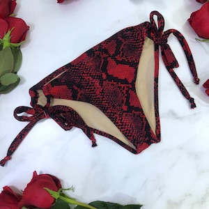 May include: Red and black snake print bikini bottom with adjustable ties.