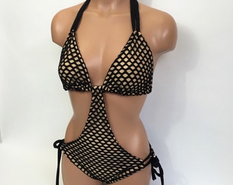 May include: Black and beige mesh one-piece swimsuit with a halter top and cutouts. The swimsuit has adjustable straps and ties at the sides.