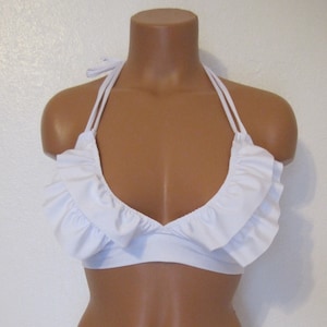 May include: White halter bikini top with a ruffled trim. The top has a deep V-neckline and adjustable straps.