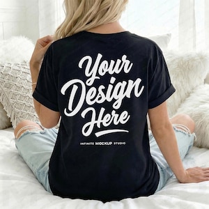 May include: Black t-shirt with the text "Your Design Here" in white script. The shirt is a mock-up, perfect for showcasing designs. The words "Infinite Mockup Studio" are printed below the main text.
