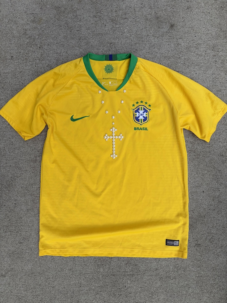 May include: A white ceramic mug with a black handle and the text "But First, Coffee" in a bold, black font. The mug is set against a blurred background, suggesting a cozy setting.