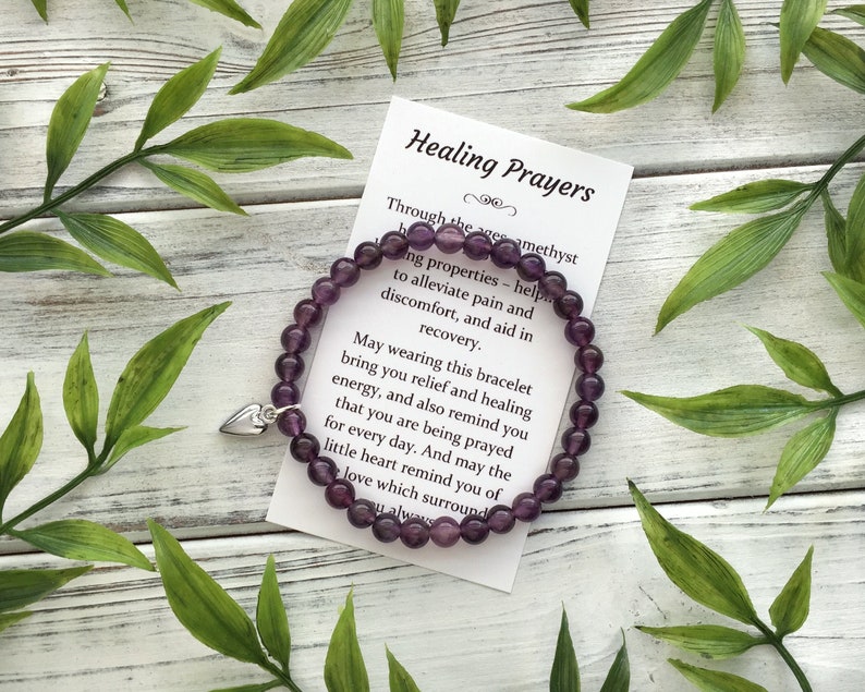 Purple amethyst bead bracelet, with 6mm beads, and a tiny silver color heart charm. Paired with a small card which says Healing Prayers at the top, and is followed by a poem describing amethyst properties and offering healing get well wishes.