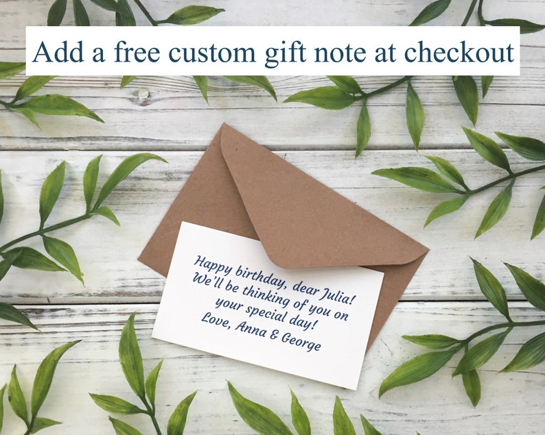 May include: A brown envelope and a white card with a handwritten birthday message. The card reads "Happy birthday, dear Julia! We'll be thinking of you on your special day! Love, Anna & George." Text at the top says "Add a free custom gift note at checkout."