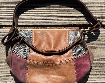 Bolso bandolera Sak Deena de piel con diseño de patchwork y estampado de plumas, con bolsillos con cremallera y correa ajustable, estilo bohemio vintage para festivales.