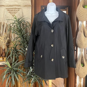 May include: A black jacket with a collared neckline and gold-colored buttons. The jacket has two front pockets and is displayed on a white mannequin. The jacket is a mid-length style.