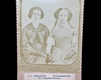 May include: Antique sepia-toned photograph featuring two women in period clothing. The image is framed with an ornate border and includes text at the bottom: "H. C. Townsend, Photographer, No. 5 Brown Avenue, Wappingers Falls, New York."