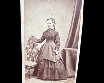 Tarjeta de visita (CDV) de la década de 1860 con la imagen de una mujer menuda con un hermoso vestido. Sello NH en el reverso.