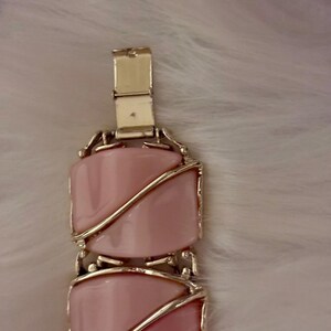 Puede incluir: Un brazalete vintage con piedras rosas rectangulares engastadas en metal dorado. El brazalete tiene un cierre de broche y un patr&oacute;n repetitivo de piedras rosas. El dise&ntilde;o es elegante y cl&aacute;sico, adecuado para diversas ocasiones.
