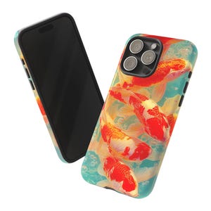May include: A phone case featuring a vibrant design of koi fish in shades of red, orange, and white against a light blue background. The case is shown with a black phone, showcasing the colorful artwork. The design includes bubbles, adding to the aquatic theme.