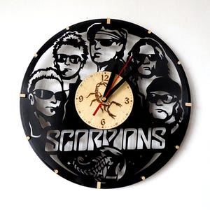 May include: Black vinyl record clock featuring a silhouette of the band Scorpions with the band name in silver lettering. The clock face is a separate round piece with a scorpion design.