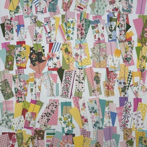 May include: A collection of colorful fabric scraps in various shapes and sizes. The scraps feature floral, striped, and polka dot patterns in shades of pink, yellow, green, and blue. Each piece is sewn with a zig-zag stitch, creating a patchwork effect.