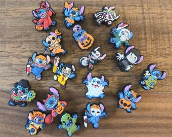 May include: A selection of colourful shoe charms featuring a blue alien-like cartoon character in various Halloween costumes. The charms include a vampire, ghost, and pumpkin. The rubber charms are designed to be attached to shoes.