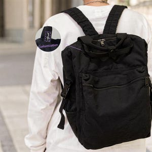 May include: Black backpack with multiple compartments, including a front zipped pocket and side pocket. The backpack has adjustable shoulder straps and a top handle. The word "April" is printed on a tag, with "Customization" below it.