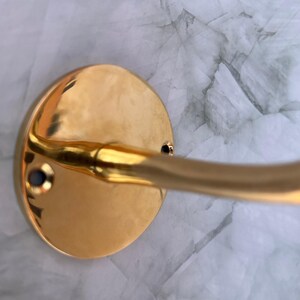 Close-up of brass hook base and screws mounted on marble wall.