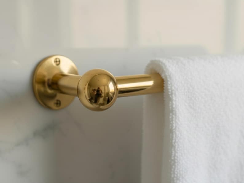 Close-up of brass towel bar end with round mount and towel draped, Moroccan craftsmanship.