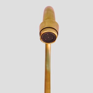 Detail view of brass faucet spout with built-in aerator.