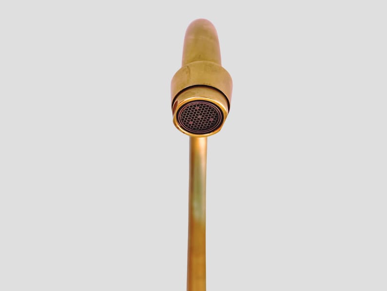 Detail view of brass faucet spout with built-in aerator.