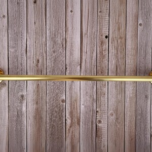 Full frontal view of brass towel bar on wood wall, minimalist farmhouse bathroom style.