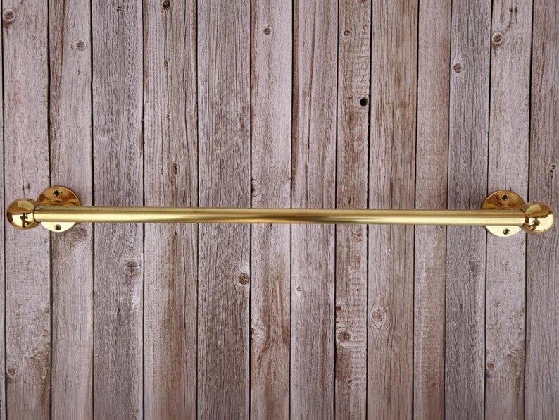 Full frontal view of brass towel bar on wood wall, minimalist farmhouse bathroom style.