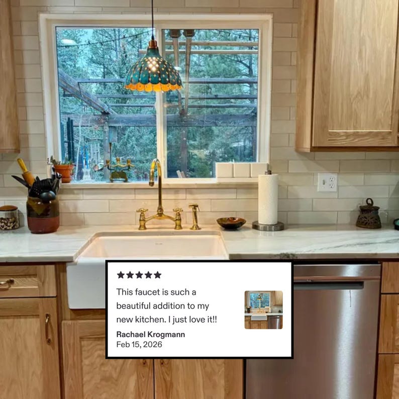Unlacquered brass bridge faucet installed in modern farmhouse kitchen with white subway tile backsplash, natural wood cabinets, and 5-star customer review.