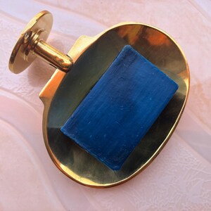 Brass wall mounted soap dish holding blue bar soap, handmade bathroom accessory.
