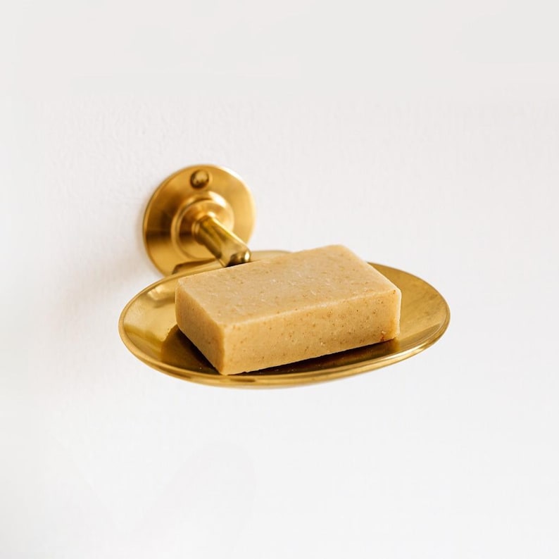 Wall mounted brass soap dish with bar of soap, vintage bathroom accessory.