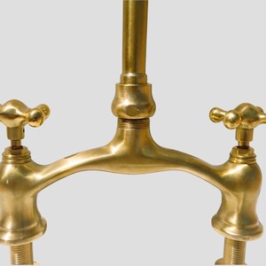 Close-up of solid brass bridge faucet body with cross handles, highlighting artisan craftsmanship and smooth unlacquered finish.