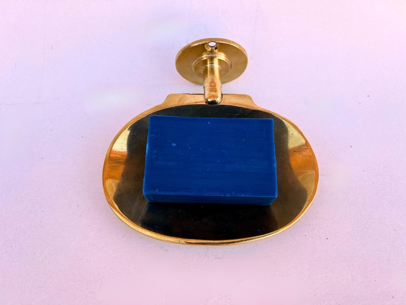 Wall mounted brass soap dish with blue bar soap, handmade bathroom accessory.