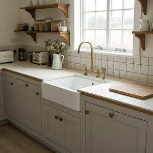 Solid brass bridge faucet in farmhouse kitchen with apron sink, wood details, and white tile backsplash for a vintage look.