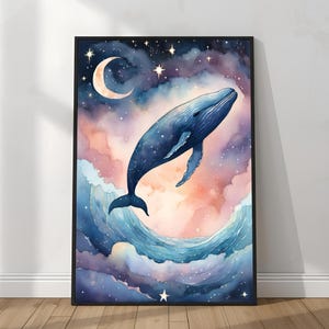 May include: Watercolor painting of a blue whale leaping from ocean waves into a starry night sky. The artwork features a crescent moon, stars, and pastel-colored clouds in shades of pink, purple, and blue. The framed art piece is displayed against a white wall.