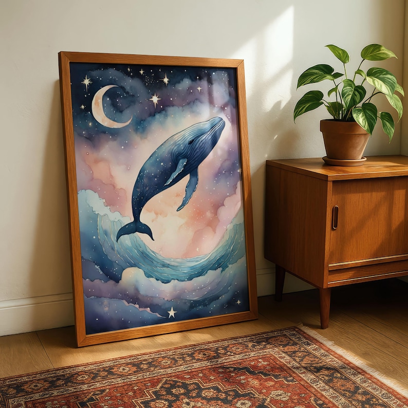 Dreamy nursery wall art featuring a majestic blue whale leaping through colorful galaxy clouds under a crescent moon and stars. Watercolor style cosmic ocean print in a wooden frame, perfect for a whimsical bedroom decor.
