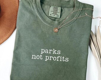May include: A moss green t-shirt with the text "parks not profits" printed in white on the front. The shirt is made of a soft, comfortable material and has a relaxed fit.