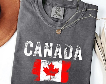 May include: A gray t-shirt with a distressed white graphic of the word "CANADA" and a red and white Canadian flag with a white maple leaf.