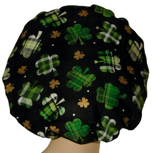 May include: Black shower cap with a green and white plaid shamrock pattern. The shamrocks are scattered across the cap and are outlined in gold.