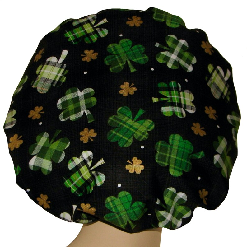 May include: Black shower cap with a green and white plaid shamrock pattern. The shamrocks are scattered across the cap and are outlined in gold.