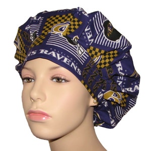 May include: A purple and gold patterned surgical scrub hat with the Baltimore Ravens logo and team name. The hat is made of a soft, comfortable fabric and is designed to be worn by medical professionals.