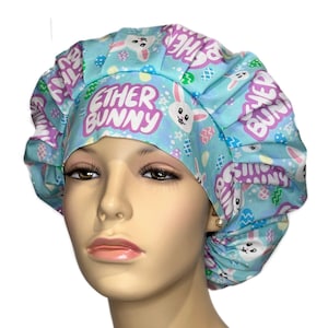 May include: A blue and purple scrub hat with a white bunny and Easter egg pattern. The hat says "Ether Bunny" in purple letters.