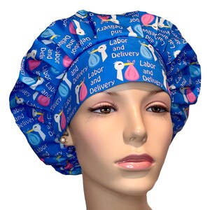 May include: Blue and pink surgical scrub hat with a pattern of storks and the text "Labor and Delivery".