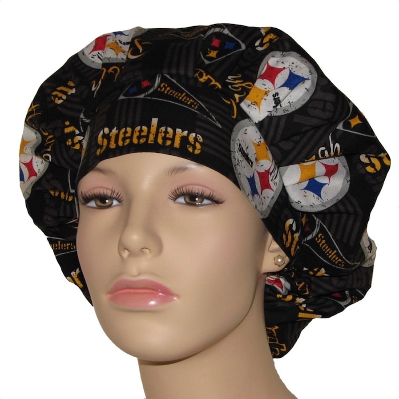 May include: Black scrub hat with a Pittsburgh Steelers logo and the word "Steelers" repeated throughout the fabric.