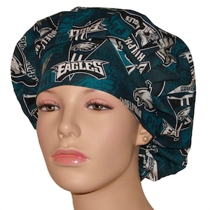 May include: Green and white scrub hat with a Philadelphia Eagles pattern. The hat features the team logo, the words "Eagles" and "Philadelphia", and other team-related graphics.