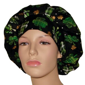 May include: Black scrub hat with a green shamrock pattern. The shamrocks are green and white plaid with gold accents.