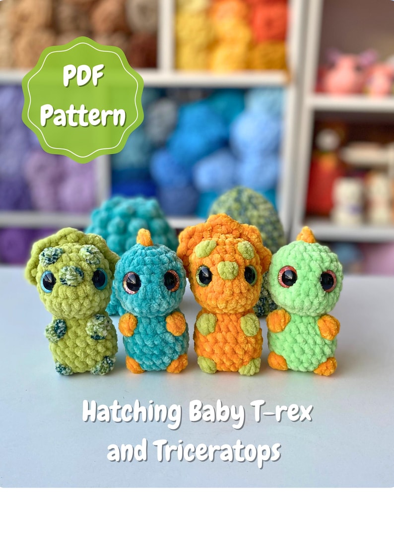May include: A collection of four crocheted baby dinosaur toys in shades of green, blue, and orange. The toys have large, expressive eyes and are labeled "Hatching Baby T-rex and Triceratops". A green and white PDF pattern label is in the top left.