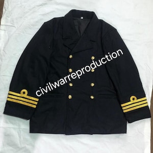 Pode incluir: Casaco azul marinho de abotoamento duplo com botões dourados e listras douradas nas mangas. O casaco tem um design clássico, com gola entalhada e duas fileiras de botões. O texto "civilwarreproduction" é visível.
