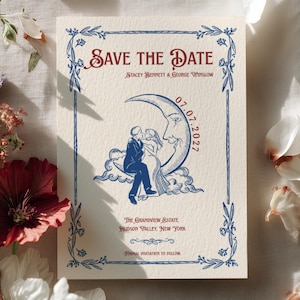 Op de afbeelding: Een crèmekleurige Save the Date-kaart met een blauwe illustratie van een koppel dat op een maansikkel zit. De tekst luidt Save the Date, Stacey Bennett & George Winslow, 07.07.2027, The Grandview Estate, Hudson Valley, New York, Formal invitation to follow.