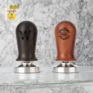 May include: Two wooden coffee tamper bases with personalized engravings. One is dark wood with the name "Wendy" and the other is light wood with the name "Vivien" in a wreath.