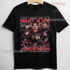 May include: Black t-shirt with a graphic design featuring Seth Jarvis, a hockey player, and his name. The design includes multiple images of the player in his hockey uniform, with the team's logo visible.