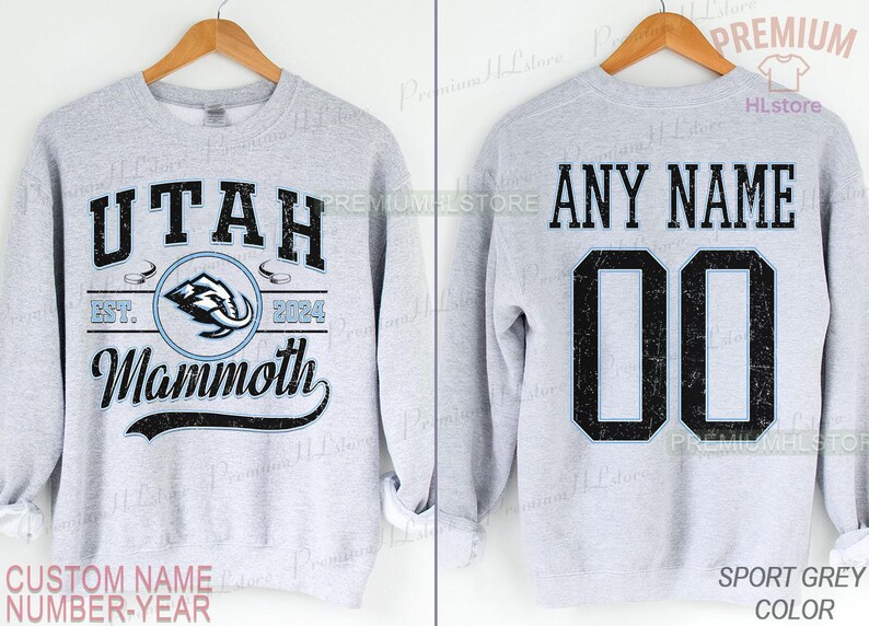 K&ouml;nnte beinhalten: Hellgraues Sweatshirt mit der Aufschrift "UTAH Mammoth" und einem Mammut-Logo auf der Vorderseite. Auf der R&uuml;ckseite steht "ANY NAME" und die Nummer "00". Das Sweatshirt ist sportgrau.