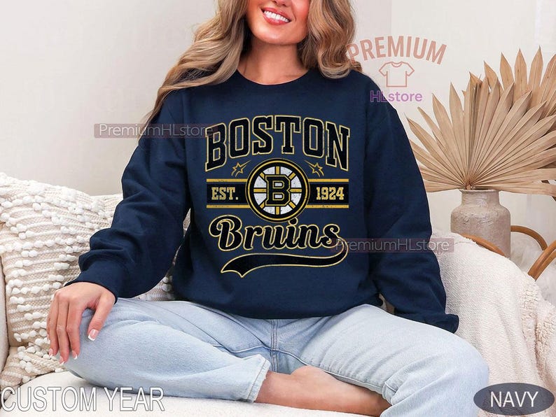 Puede incluir: Sudadera azul marino con el texto "BOSTON Bruins" en letras doradas y blancas. El dise&ntilde;o incluye el logotipo de los Bruins y el a&ntilde;o "1924". Una sudadera cl&aacute;sica de cuello redondo.