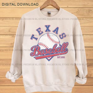 May include: A beige sweatshirt with a baseball graphic. The graphic includes the word "TEXAS" in blue, a baseball, and the word "Baseball" in red script. The text "EST. 1835" is also included.